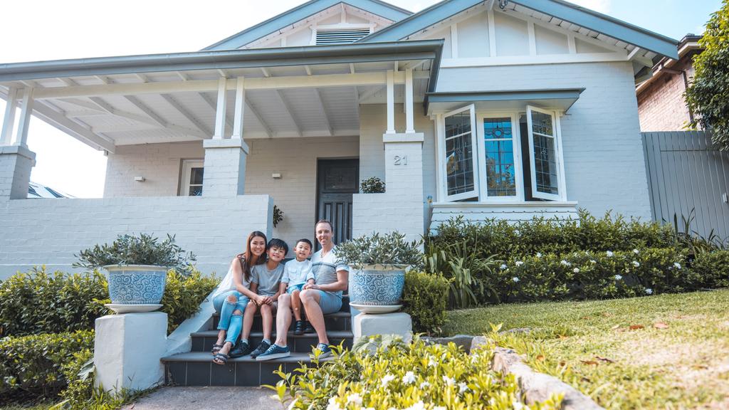 family sitting in front of their home